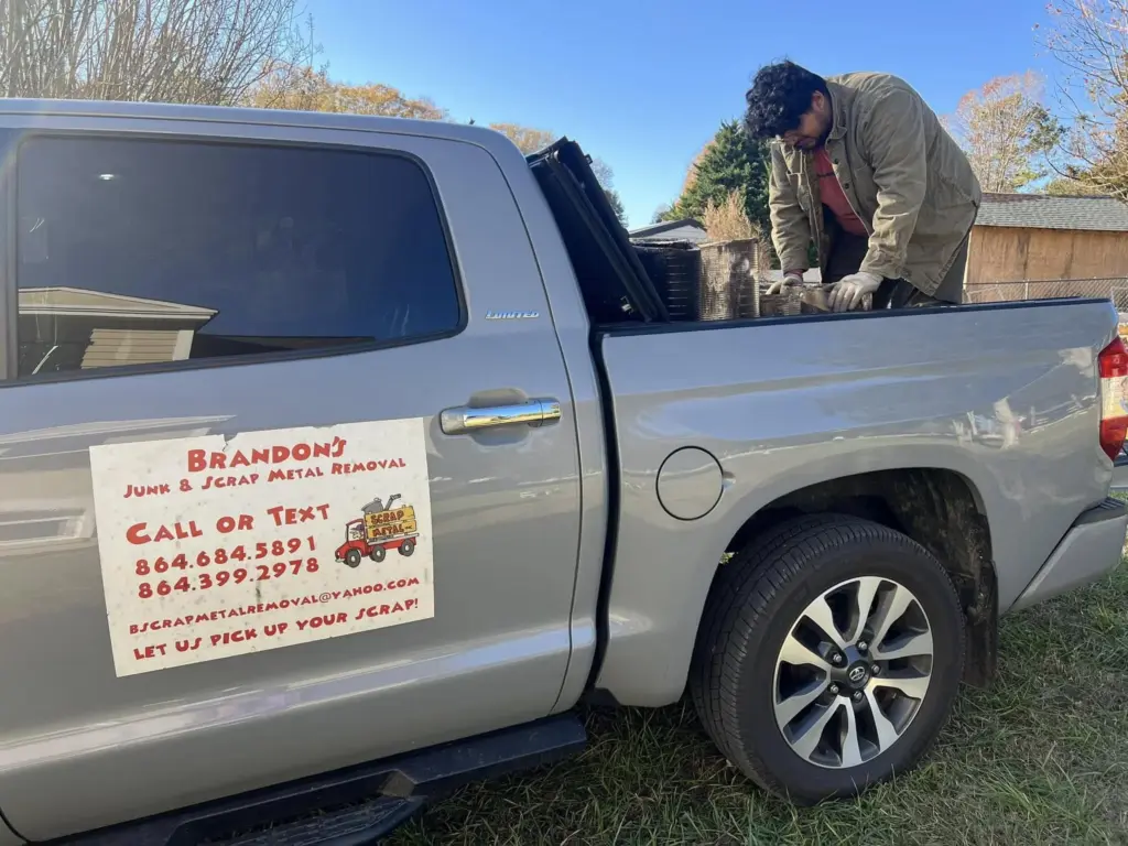 Worker handling tools and debris during junk removal job in Greenville SC
